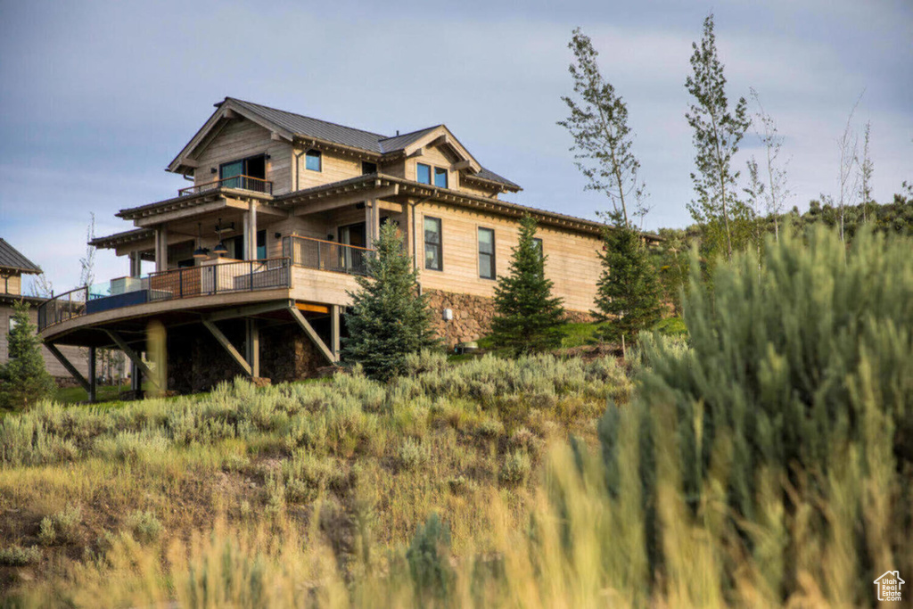 Rear view of property with a deck, metal roof, and stone siding