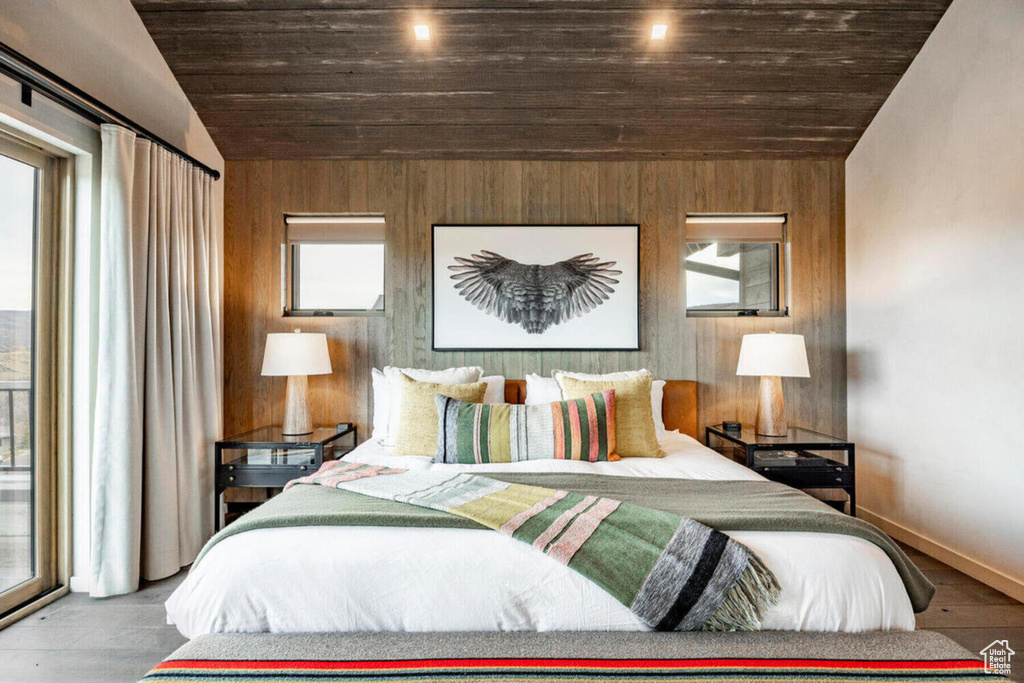Bedroom with wooden walls, baseboards, wood finished floors, lofted ceiling, and wood ceiling