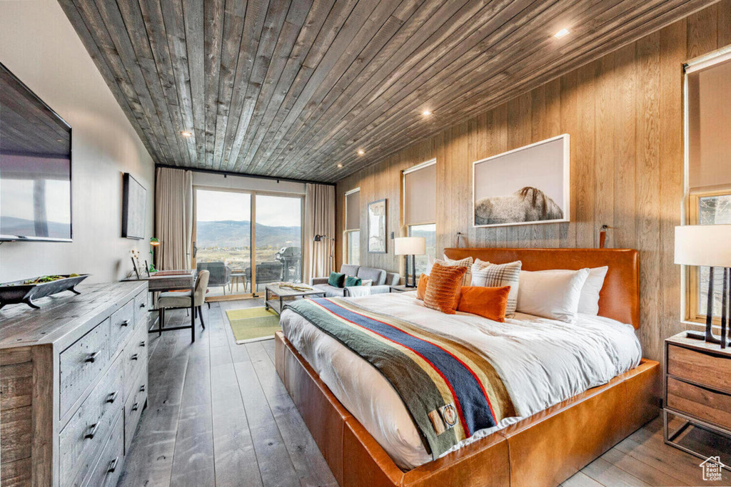 Bedroom featuring wooden walls, wood ceiling, hardwood / wood-style floors, and access to exterior