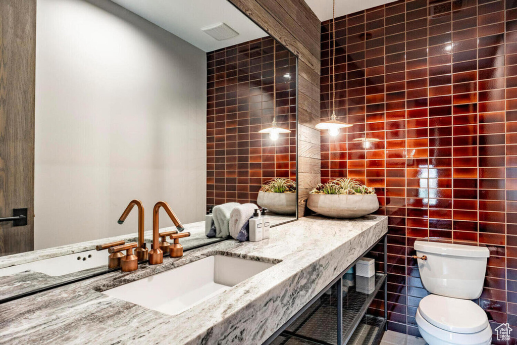 Bathroom featuring toilet, tile walls, tile patterned flooring, and vanity
