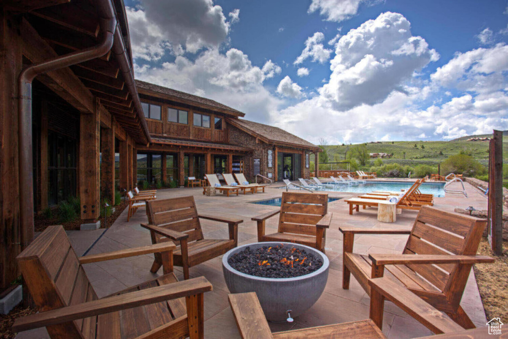 View of patio featuring a community pool and a fire pit