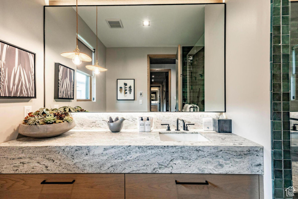 Full bathroom with visible vents, tiled shower, and vanity