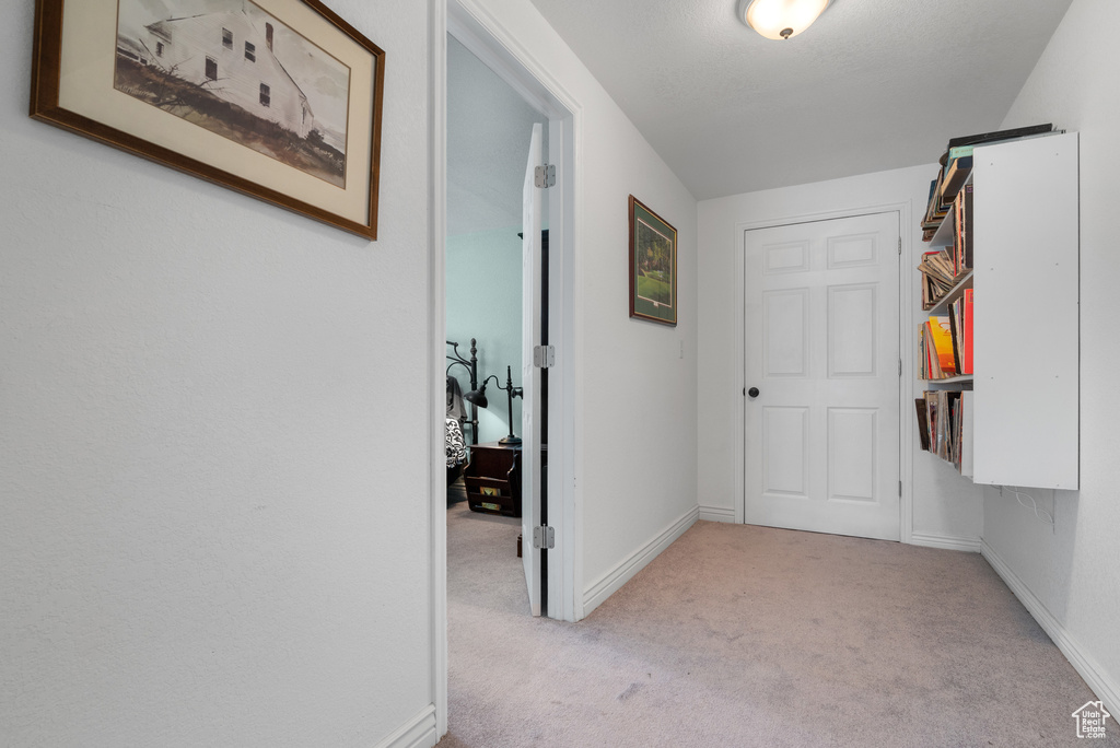 Corridor featuring light colored carpet and baseboards