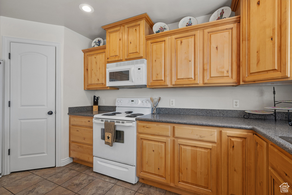 Kitchen with recessed lighting, dark countertops, and white appliances