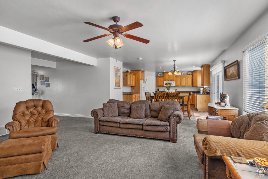 Living area featuring baseboards, ceiling fan, and light carpet