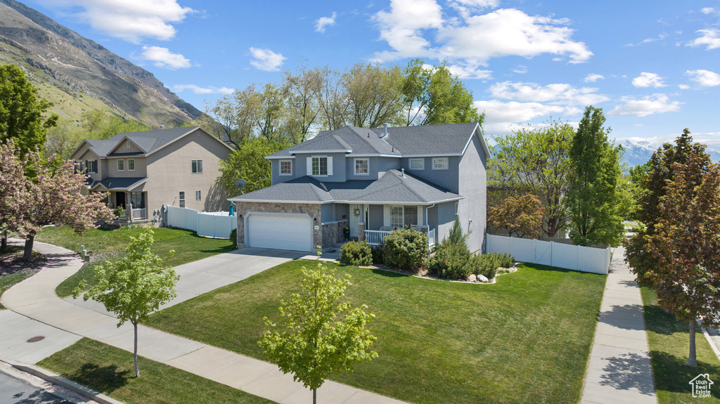 Traditional-style home with covered porch, a front yard, a garage, fence, and concrete driveway