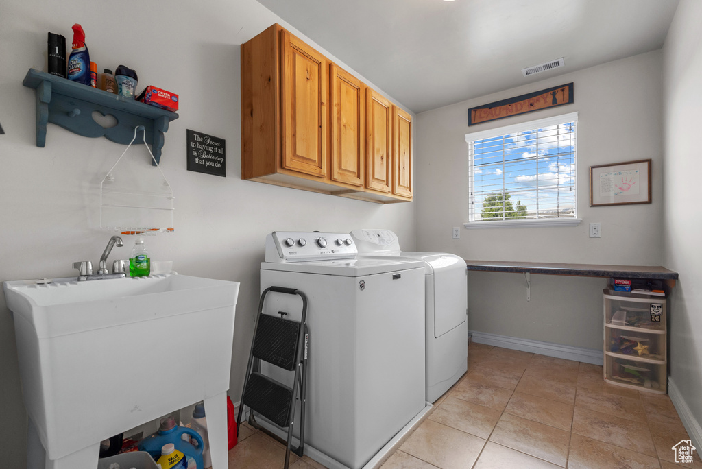Laundry area with washing machine and clothes dryer, visible vents, cabinet space, a sink, and light tile patterned floors