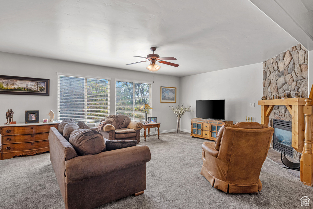 Living area with baseboards, a ceiling fan, carpet, and a fireplace
