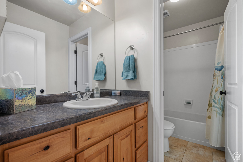 Full bath with vanity, tile patterned floors, shower / bath combination with curtain, and toilet
