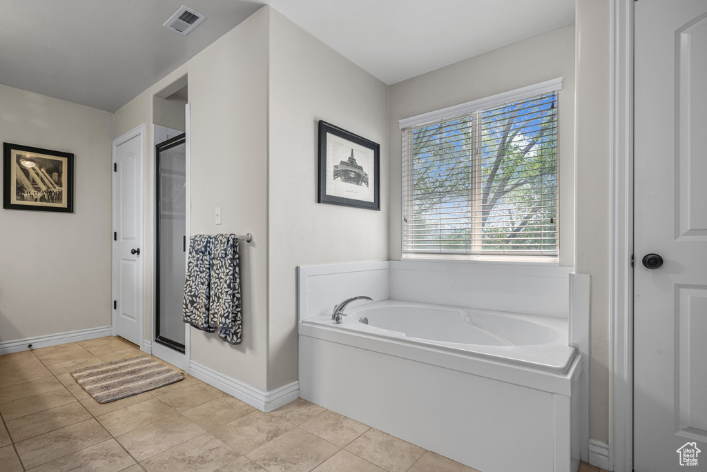 Full bathroom featuring a bath, visible vents, a stall shower, baseboards, and tile patterned floors