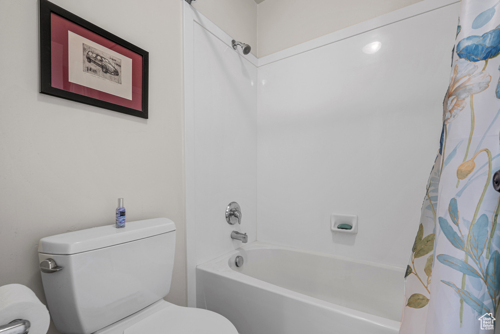 Full bathroom with toilet and shower / bath combination with curtain