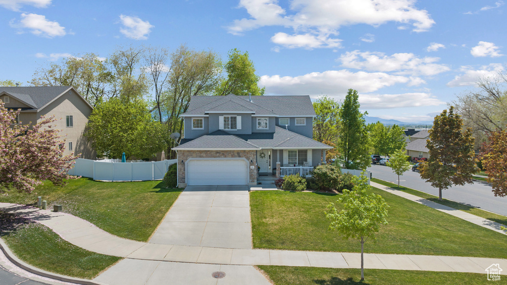Traditional-style home featuring fence, a garage, a front yard, covered porch, and driveway