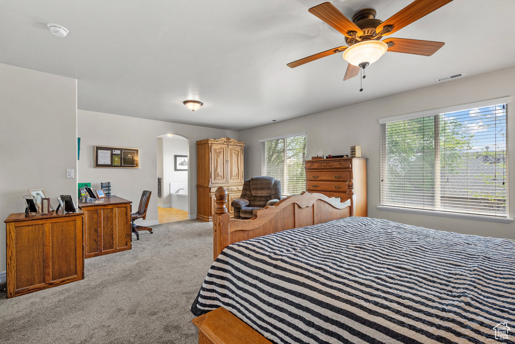 Bedroom featuring arched walkways, light colored carpet, and visible vents
