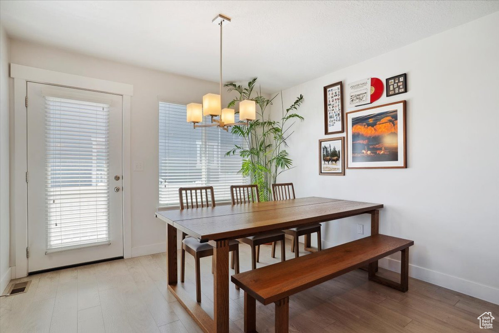 Dining room featuring baseboards, a notable chandelier, light wood finished floors, and visible vents