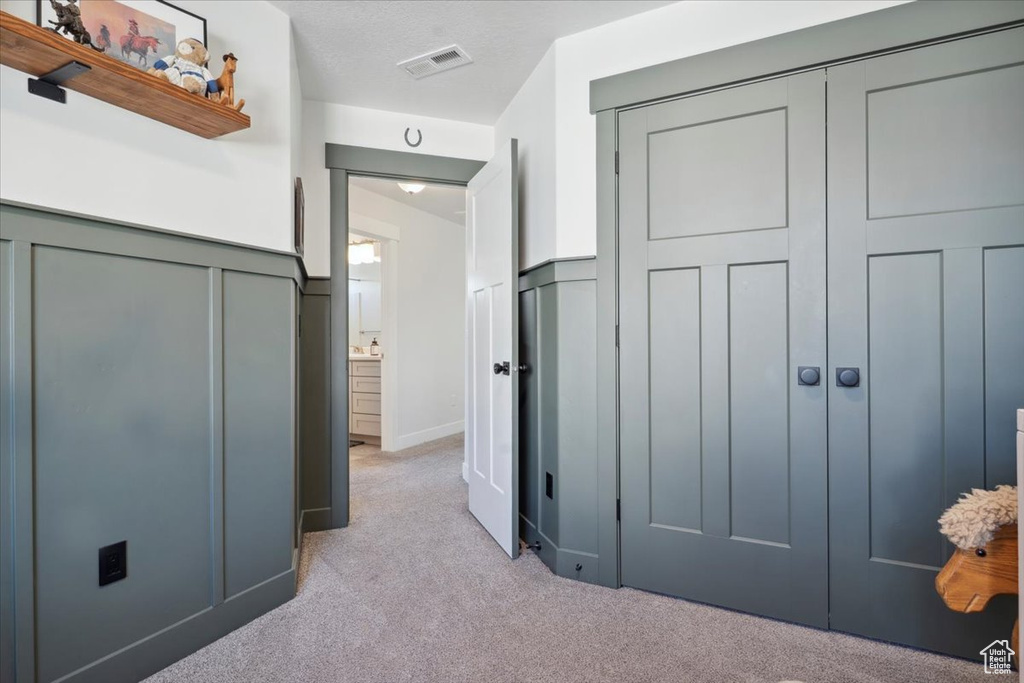 Unfurnished bedroom featuring visible vents, light carpet, and a closet