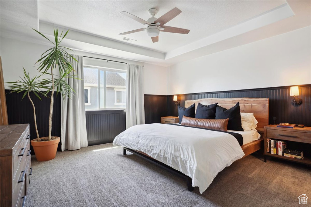 Bedroom featuring visible vents, carpet flooring, ceiling fan, and a wainscoted wall