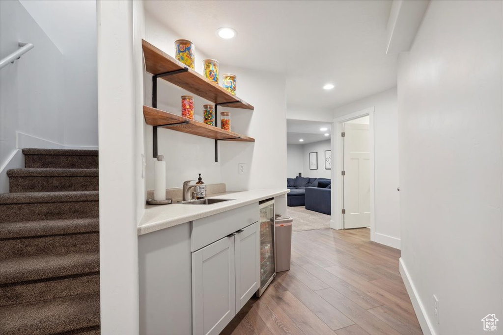 Bar with light wood-type flooring, stairway, a sink, wine cooler, and recessed lighting