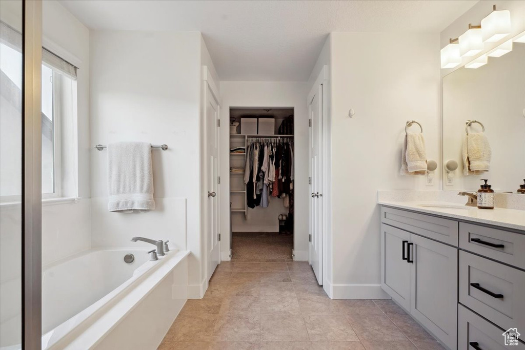 Full bathroom with a walk in closet, a wealth of natural light, a bath, and vanity