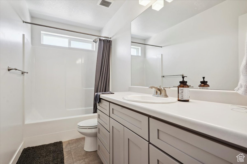 Bathroom featuring visible vents, tile patterned flooring, shower / bath combo, vanity, and toilet