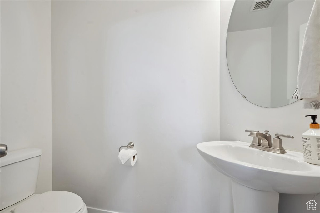 Bathroom featuring a sink, toilet, and visible vents
