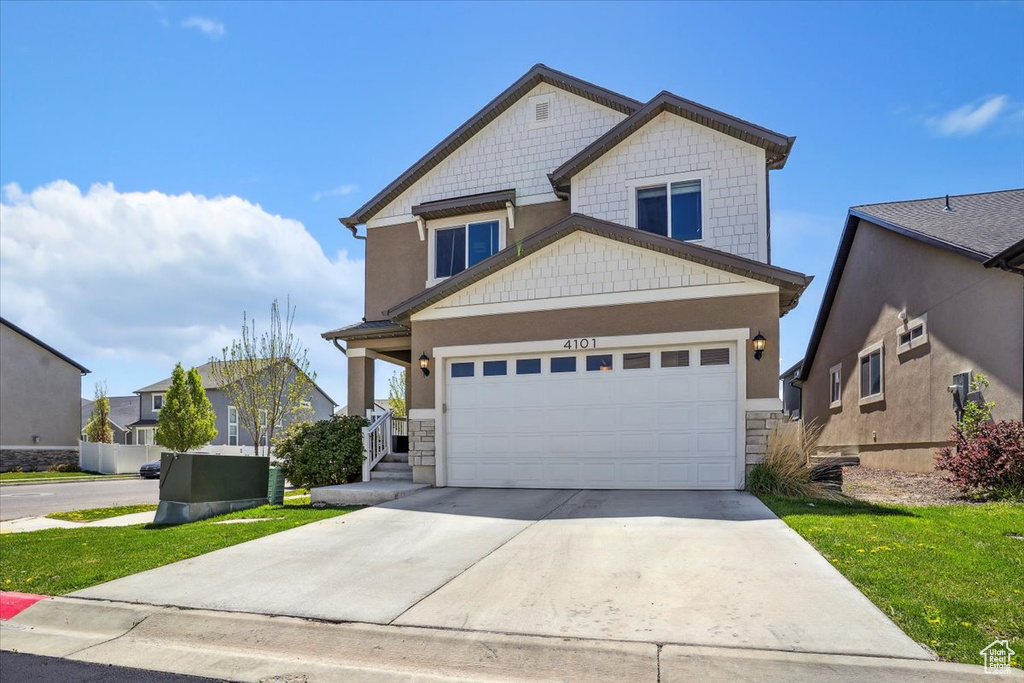 View of front of house featuring concrete driveway, stone siding, and a front lawn
