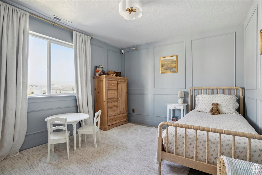 Bedroom with multiple windows, a decorative wall, a textured ceiling, and visible vents