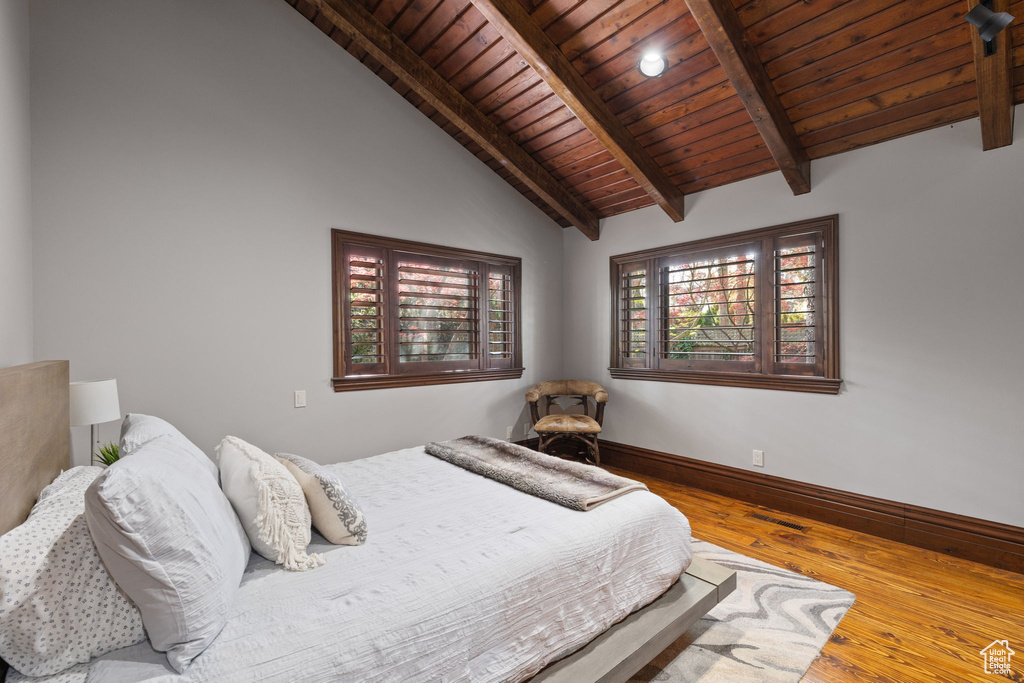 Bedroom featuring wood ceiling, vaulted ceiling with beams, baseboards, and wood finished floors