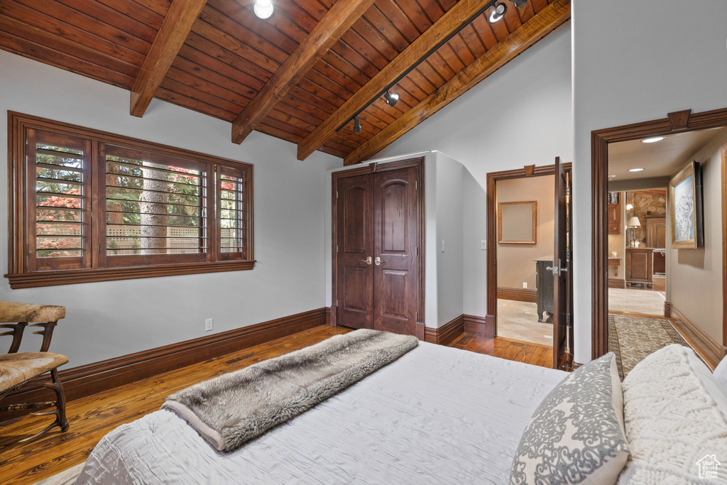 Bedroom with wooden ceiling, baseboards, a closet, vaulted ceiling with beams, and hardwood / wood-style floors