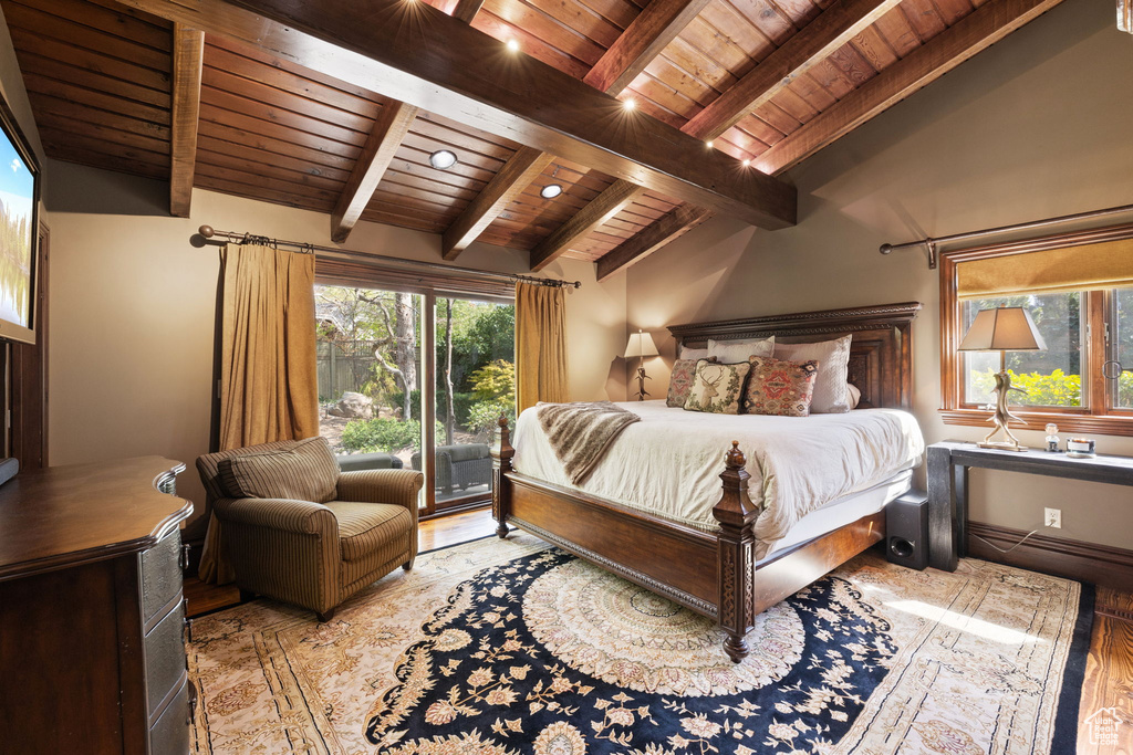 Bedroom with lofted ceiling with beams, wood ceiling, wood finished floors, and access to exterior