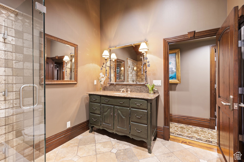 Full bath featuring baseboards, a shower stall, and vanity