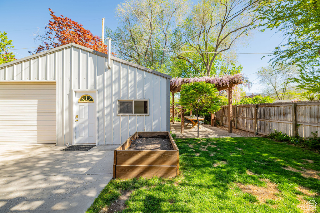 View of outdoor structure with fence and a garage