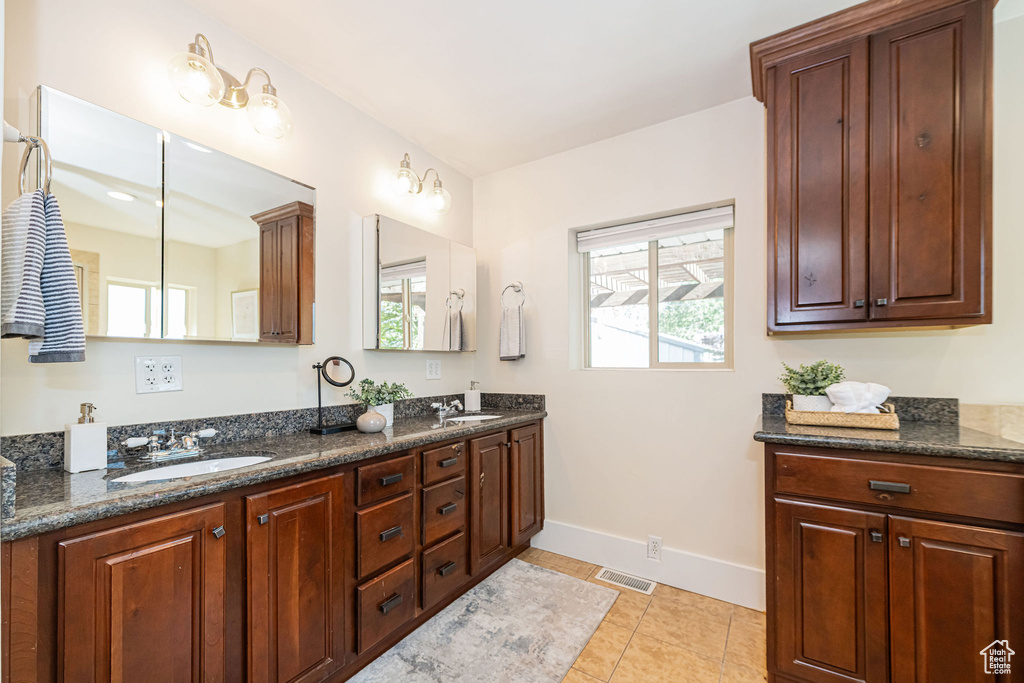 Full bathroom featuring double vanity, baseboards, visible vents, and a sink