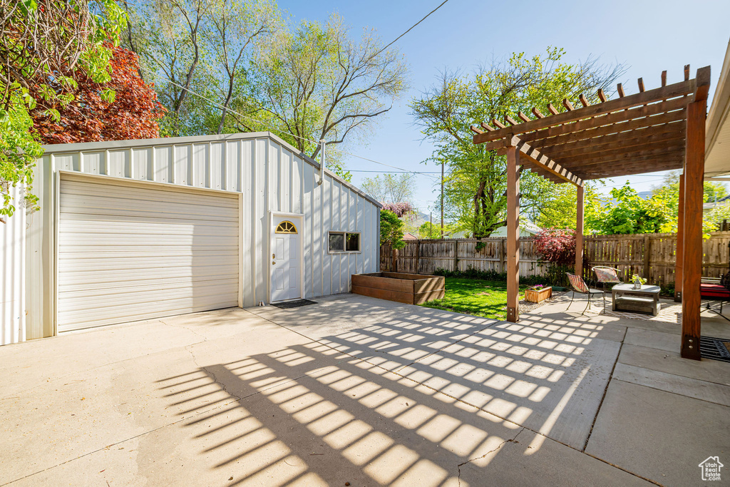 View of patio featuring a garage, fence, a pergola, and driveway