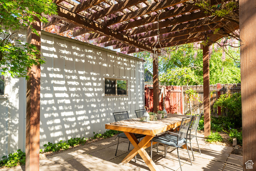 View of patio featuring outdoor dining area, fence, and a pergola