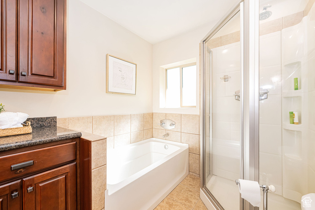 Full bathroom featuring tile walls, tile patterned flooring, a stall shower, and a garden tub