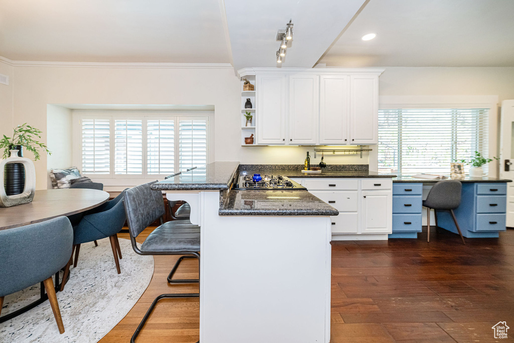 Kitchen with white cabinetry, a kitchen breakfast bar, dark wood-type flooring, and a peninsula