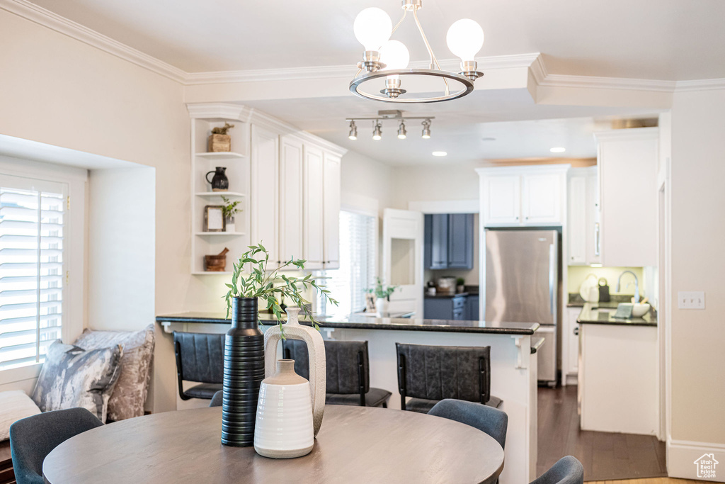 Dining space featuring dark wood-type flooring, ornamental molding, and a notable chandelier