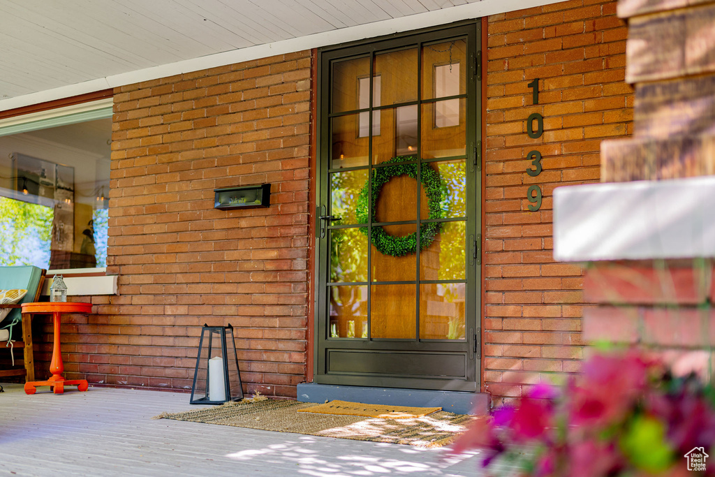 Doorway to property with covered porch and brick siding