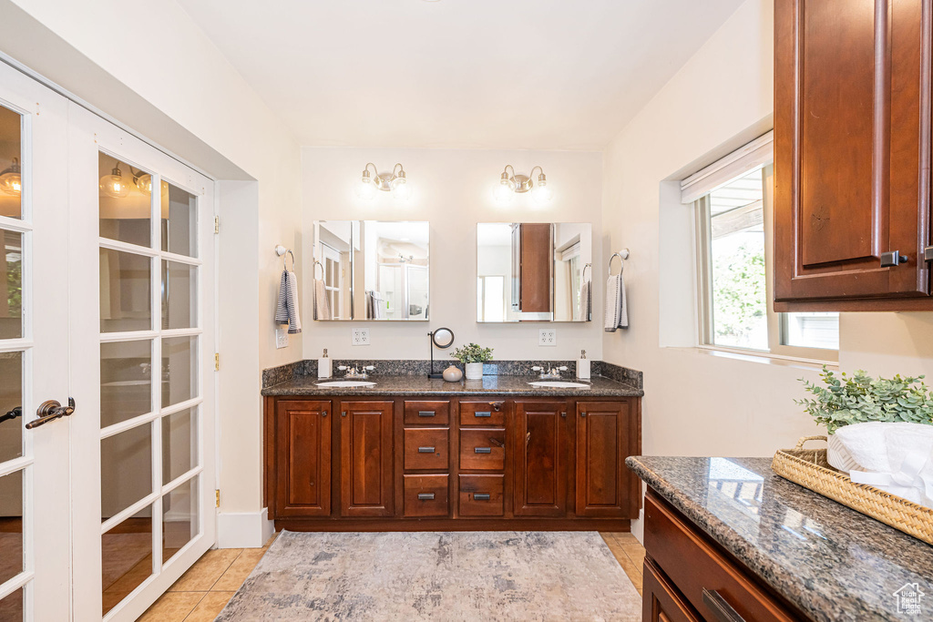 Full bath with double vanity, a sink, and tile patterned flooring