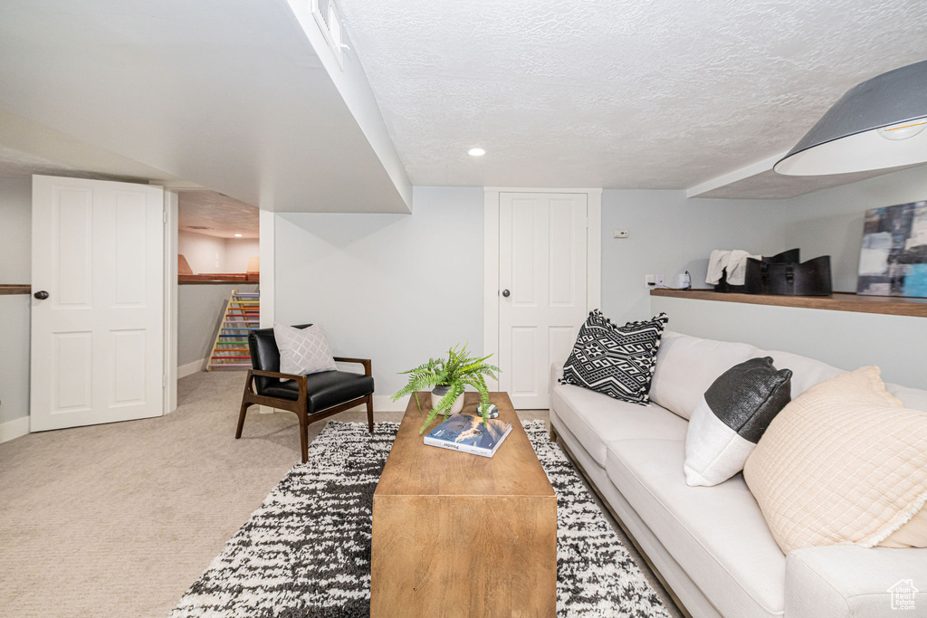 Carpeted living area featuring baseboards, recessed lighting, and a textured ceiling