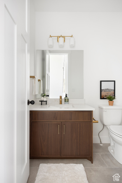 Bathroom featuring toilet, tile patterned floors, baseboards, and vanity