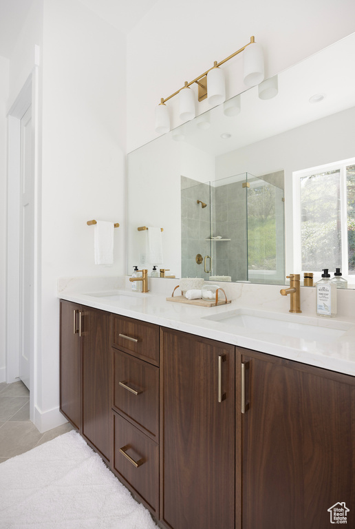 Bathroom with a sink, tile patterned floors, a stall shower, and double vanity