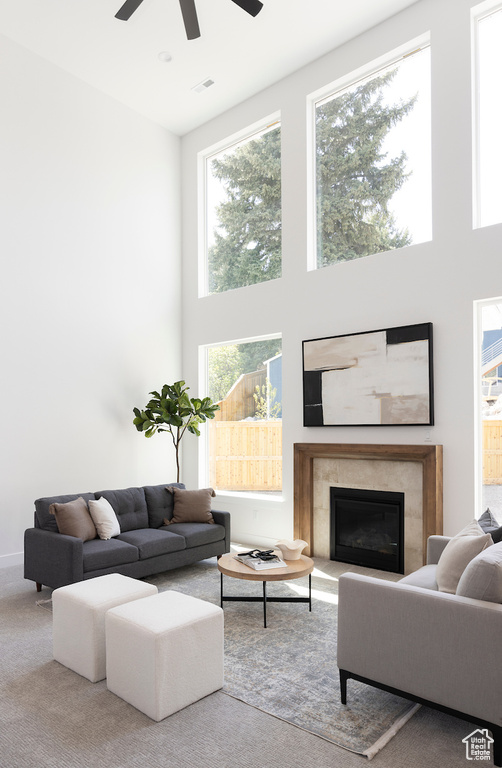 Living room featuring a high ceiling, a fireplace, ceiling fan, and visible vents