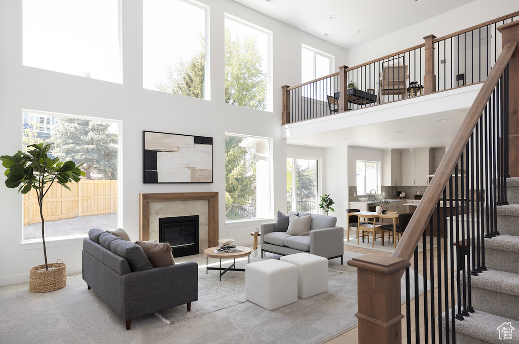 Living area with a towering ceiling, baseboards, stairway, and a high end fireplace