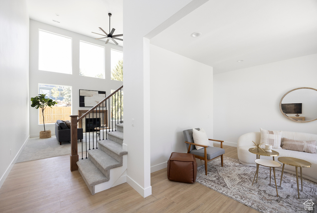 Living area with baseboards, ceiling fan, wood finished floors, and stairway