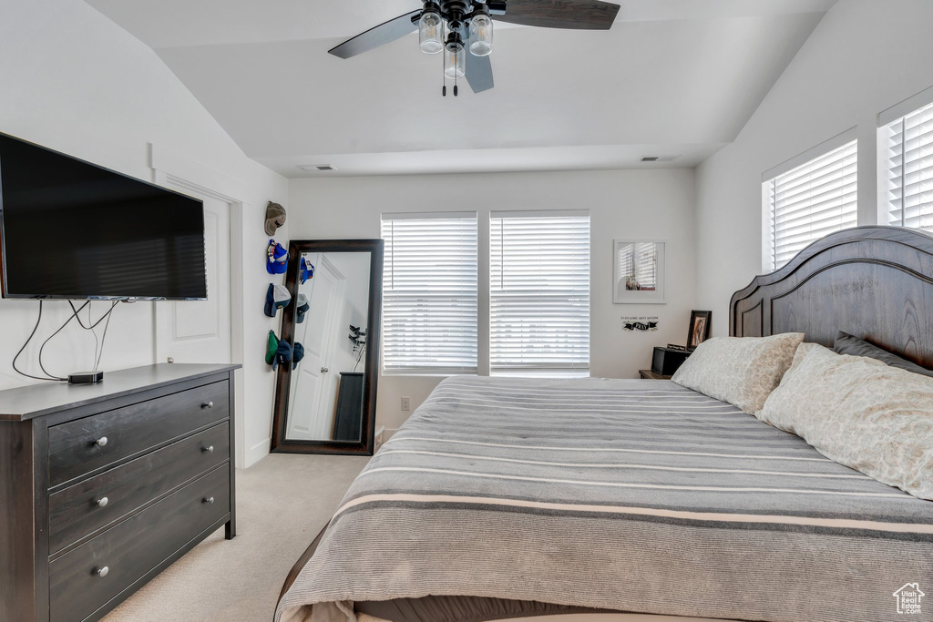 Bedroom with multiple windows, a ceiling fan, light colored carpet, and lofted ceiling