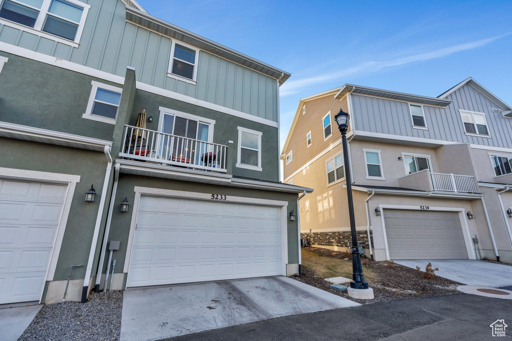 View of front of home featuring board and batten siding, an attached garage, concrete driveway, and a balcony