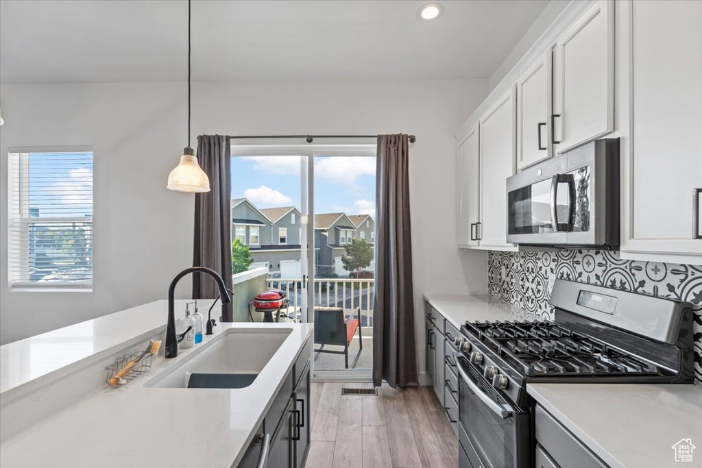 Kitchen with appliances with stainless steel finishes, light countertops, tasteful backsplash, white cabinets, and recessed lighting