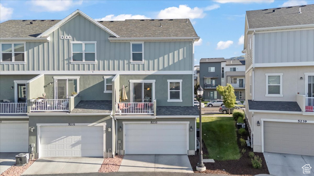 View of front of property with board and batten siding, an attached garage, a residential view, stucco siding, and driveway
