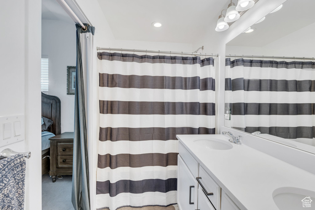 Ensuite bathroom featuring double vanity, a sink, curtained shower, and recessed lighting